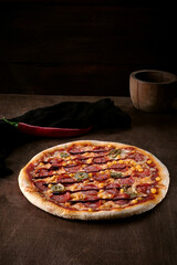 Spicy hot pepperoni pizza with corn and jalapeno peppers on a dark rustic wooden background. Cooked barbecue pizza on table Baner. Copy space