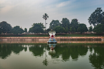 Fototapeta premium Budhha statue at lake isolated with bright sky and unique prospective