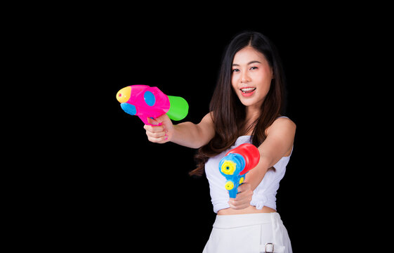 Young happy beauty Asian woman holding plastic water gun at Songkran festival, Thailand. Thai New Year's Day. Isolated on black background. - Powered by Adobe