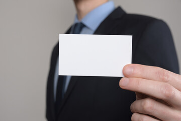 Businessman ,Business Man's hand hold showing business card - close up shot on grey background. Show a blank piece of paper. Paper visit card