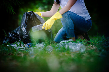 Woman hand picking up garbage plastic and Glass bottles for cleaning at park