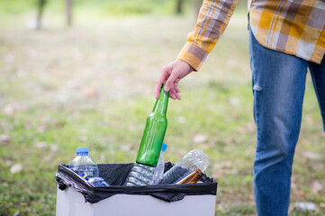 Woman hand picking up garbage plastic and Glass bottles for cleaning at park