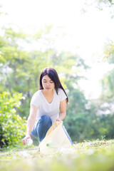 Asian Young woman hand picking up garbage plastic for cleaning at park.Environmental conservation.