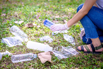 Woman hand picking up garbage plastic and Glass bottles for cleaning at park
