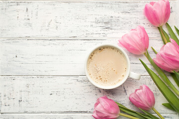 Good morning concept. Flat lay photo image of tasty cup of beverage and bunch of pastel pink color tulips on wooden rustic desk with blank empty space
