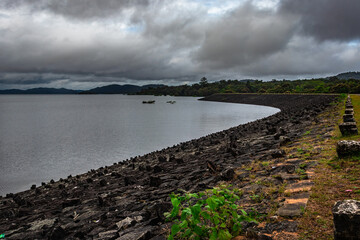 Fototapeta premium river serene back water with stone edge and dramatic cloudy sky