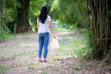Naklejka na ściany i meble Asian Young woman hand picking up garbage plastic for cleaning at park.Environmental conservation.