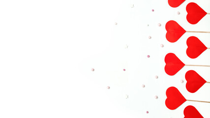 paper red hearts on a wooden skewer with round beads on a white background with a place for text, Valentine's Day celebration concept
