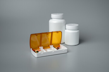 Pills and capsules in pill organizer. Medical Concept, Illustration of Pharmacy Bag with Pill Container or Pill Box on gray background. 
Disease prevention. 