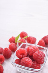 Raspberries in a bowl on a wooden textured background