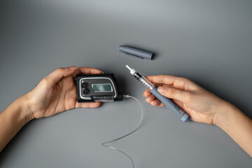 young woman holds an insulin syringe and an insulin pump in her hands. Diabetes is a disease of the endocrine system. Syringe on a gray background.