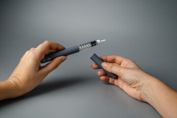 young woman holds a syringe for insulin. Diabetes is a disease of the endocrine system. Syringe on a gray background. © Ekaterina