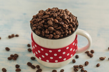 White cup full of coffee beans with red dotted tape on light blue