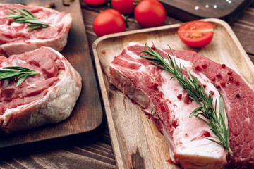 Raw beef steak with rosemary and spices on wooden board