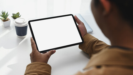 Close up view of young man Hans holding digital tablet with white screen. Blank screen for your...