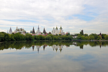 Naklejka na ściany i meble Kremlin in the Moscow district of Izmailovo on a summer day. View of the Izmailovsky Kremlin - a complex of buildings in the old Russian style and their reflection in the water of the pond