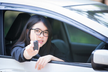 Asian woman sitting in a private car shows the keys in her hand.Selected focus
