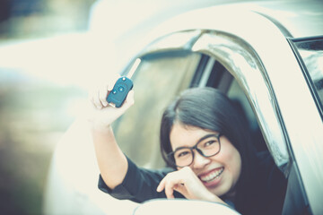 Asian woman sitting in a private car shows the keys in her hand.Selected focus