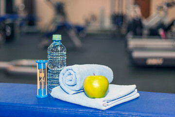 a bottle of water, a towel, an apple in the fitness room, clock watch