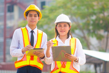 Two people Asian engineer use tablet talking check inspection plan in project civil property building construction, Man women work smart technology