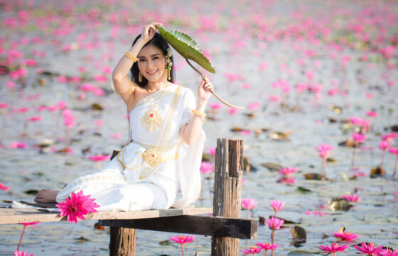Beautiful girl in White Thai dress with red lotus flowers.Thai girl in retro Thai dress,Beautiful Thai girl in traditional dress costume