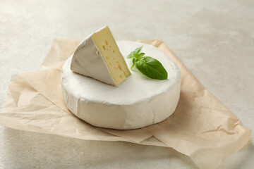 Baking paper with camembert cheese on white textured background