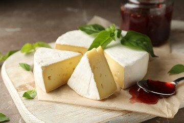 Concept of tasty eating with camembert and jam on cutting board