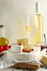Concept of tasty eating with camembert, hazelnut and wine on white table
