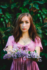 Portrait of young beautiful woman in pink dress in spring garden with lilacs. Spring background. Woman's Day. Greeting card. 