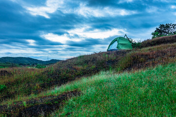 Fototapeta na wymiar camping solo at mountain top with amazing view and dramatic sky at evening