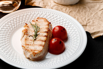 Grilled chicken breast served with cherry tomatoes on table