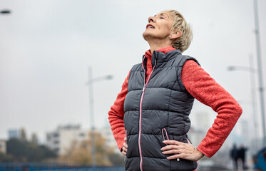 Active senior woman stretches her muscles before running through the city during the day. © Zoran Zeremski