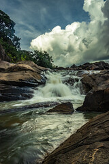 waterfall in remote forest with dramatic sky from flat angle long exposure