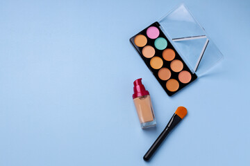 Complexion make up products and brush on blue background
