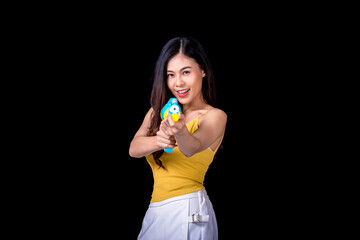 Portrait cheerful young asian woman Wearing a yellow tank top ,holding plastic water gun Smiling and having fun playing in the water Songkran festival, Songkran Thailand. isolated on black background.