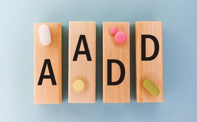 AADD Abbreviation on cubes with pill on a blue background. Close AADD - Adult Attention Deficit Disorder
