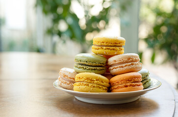 A plate with colorful macaroons cakes for delicious French breakfast in a sunny room