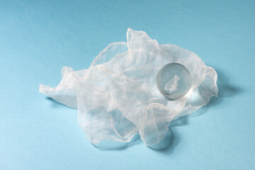 Glass ball on white organza textile, blue background
