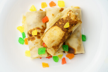 Pancakes on a plate. Top view of a white plate with thin pancakes stuffed with candied fruits