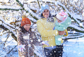 family throwing snow in the winter forest, mother and children, bright sunlight and shadows on the snow, beautiful nature