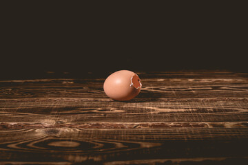 Empty chicken egg with a hole on a wooden background. A studio photo with hard lighting.