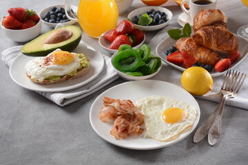 Healthy breakfast. Toast with avocado and egg, bacon and eggs, fresh and dried fruits, fresh juice