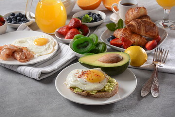 Healthy breakfast. Toast with avocado and egg, bacon and eggs, fresh and dried fruits, fresh juice