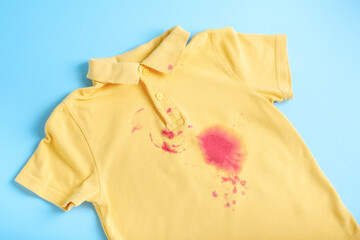  dirty stain from the juice on a children's T-shirt. isolated on blue background. 