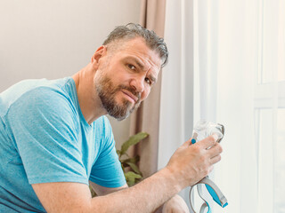 Unhappy shocked man with chronic breathing issues surprised by using  CPAP machine sitting on the...
