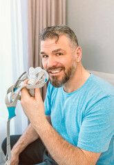 Mature happy man with chronic breathing issues considers using sitting on the bed in bedroom with...