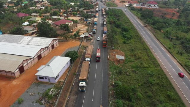 Aerial trucks backlog rural village highway Ghana Africa part 1. Busy congested market area, truck parking rural village. Buy and sell products, food, low income poverty of Africa. Roadside market.