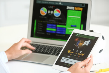 Woman placing sports bet with tablet computer and laptop, closeup
