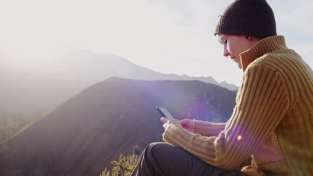 Smiling traveling woman browsing smartphone in mountains