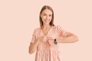 Beautiful woman with wristwatch on color background
